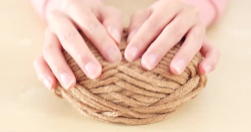 Woman's Hands Manipulate Ball of Brown Yarn