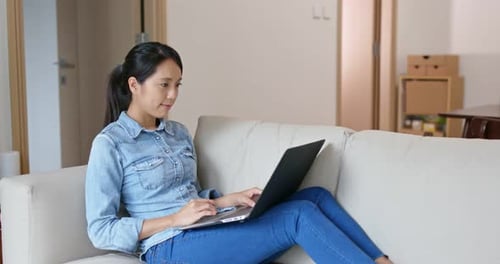 Woman Using Laptop on Couch in Bright Room