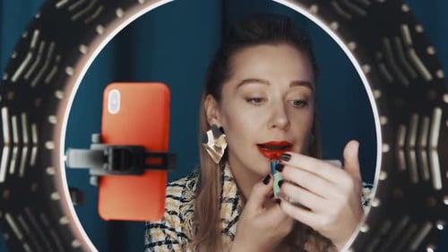 Vídeo tutorial de grabación de mujer aplicando lápiz labial rojo