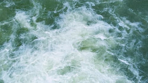 Aerial view of river waterfall with clear turquoise water falling down with thick white foam.