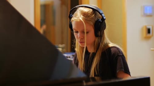 Blonde Child Plays Piano Wearing Headphones