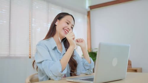 Mulher asiática atraente estudante colocando fones de ouvido, ouvir música e cantar durante o ensino doméstico