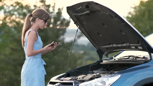 Woman Inspecting Car Engine While Using Cellphone