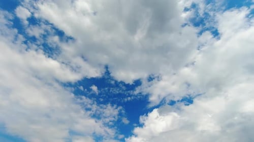 Fluffy White Clouds Float Across Blue Sky