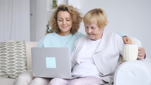 Woman and Senior Woman Using Laptop on Couch