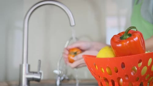 Washing Fresh Tomato Under Faucet in Kitchen