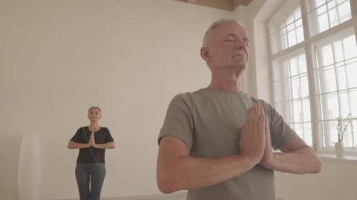 Senior Couple Meditating Indoors in Yoga Studio