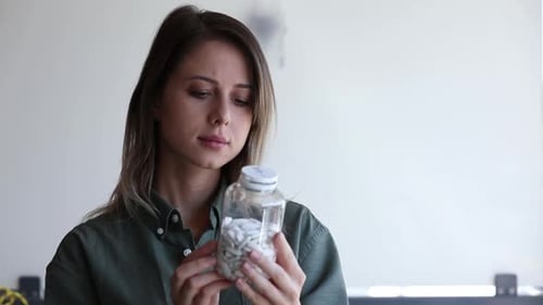 Woman Examining Bottle of Pills Close-up