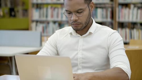 Focused Student Using Laptop in a Library