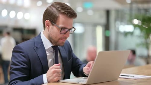 Man Celebrating Success at Work Using Laptop