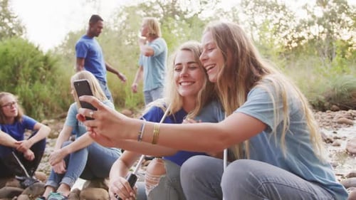 Mid adults volunteering and women taking a selfie during river clean-up day