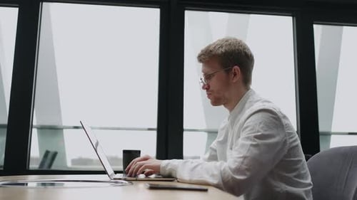 Businessman is Working with Notebook in Modern Office or Coworking Space Surfing Internet for Info