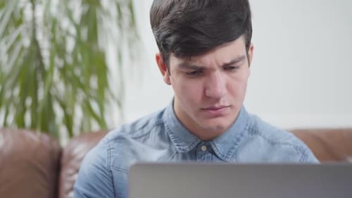 Young Adult Works on Laptop in Home Setting
