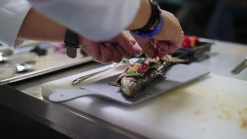 Chef Garnishing Whole Fish with Colorful Herbs