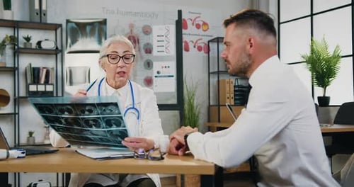 Doctor in Modern Medical Office and Listening Her Explanation about His X-ray scan