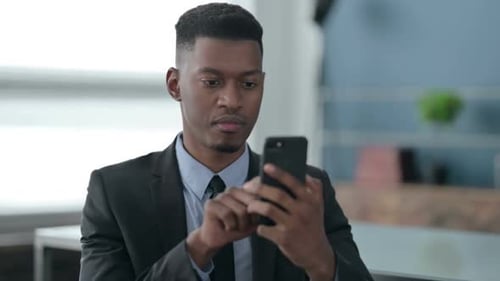 Young Adult Man Using Smartphone in Office Setting