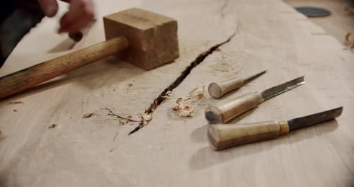 Woodworker Carving Wood with Chisel and Mallet