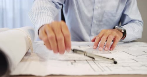 Mid-section of architect working on blueprint