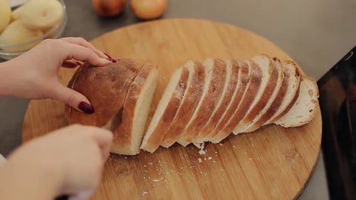 Woman Cuts Fresh Bread on a Wooden Board. Flour Around. Hands with Red Nails. Close Up.