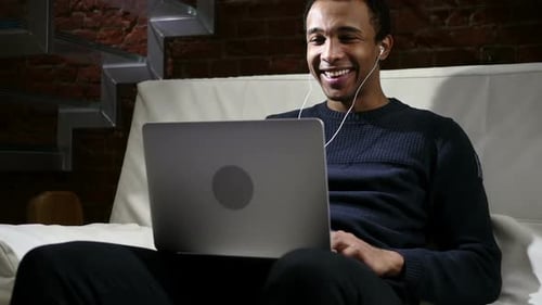 Young Man Smiling During a Video Call on Laptop