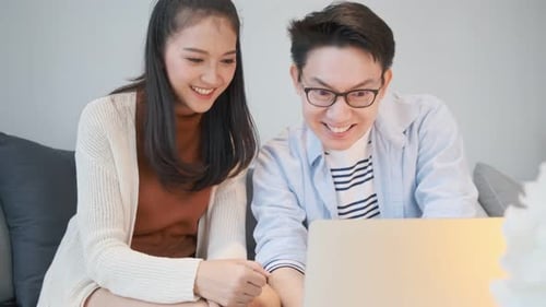Young Couple Laughing at Laptop on Couch