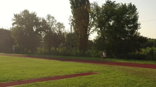 The man training jogging at the stadium in summer