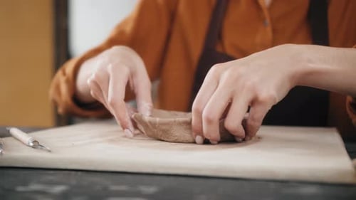 Woman shaping small clay bowl with her hands