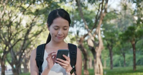 Woman Using Phone in Green Urban Park