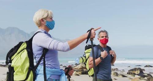 Senior Couple Walking on Beach Wearing Face Masks