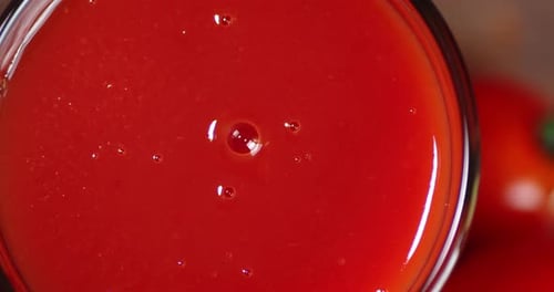 Tomatensaft in einem Glas mit Luftblasen dreht sich langsam.