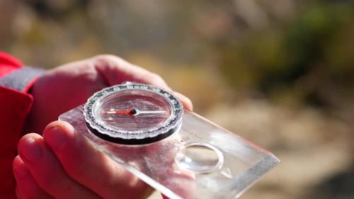 Close up on an old scratched magnetic compass being used in an emergency survival situation to find