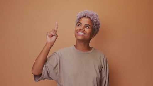 African Female Makes Gesture with Index Finger Points Upwards for Advertisment