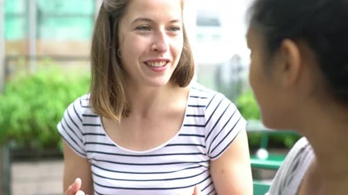Two Friends Laughing and Talking at a Cafe