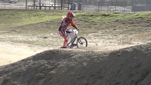 A young woman bmx rider riding on dirt track.