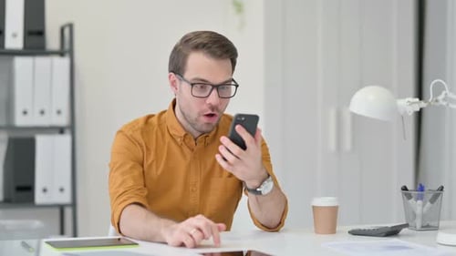 Man Celebrates Achievement While Looking At Phone