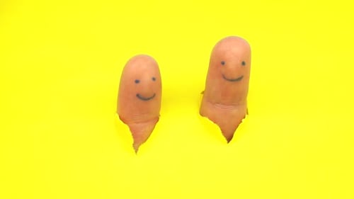 Painted Finger Faces Appear Through Ripped Yellow Paper