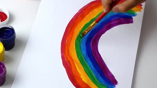 Child Hand Painting a Colorful Rainbow with Brush