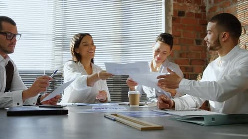 Professionals Collaborate on Documents at Office Meeting