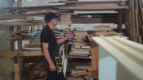 Carpentry Workshop a Man Worker Walks By the Shelves and Takes a Triangle Board
