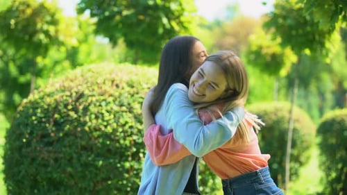 Two Young Women Sharing Joyful Hug in Park