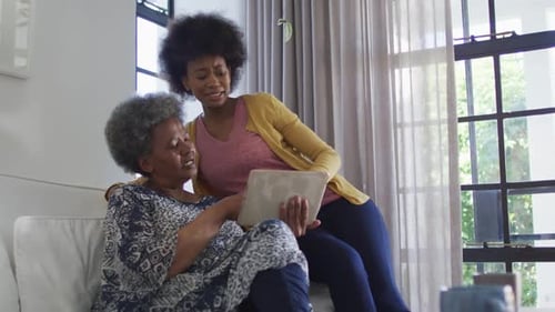 Woman and Senior Looking at Tablet Together Indoors