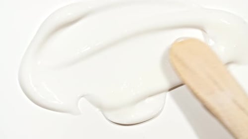 Spreading White Cream Lotion with a Wooden Spatula