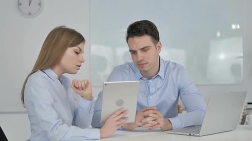 Business Colleagues Discussing Data on Tablet in Office