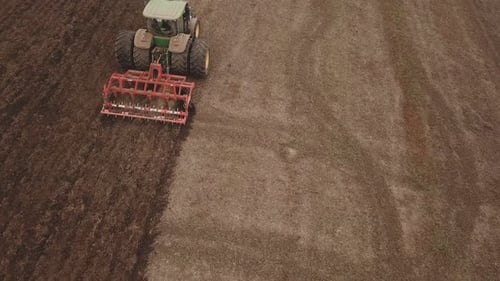 A Large Tractor Plows a Field