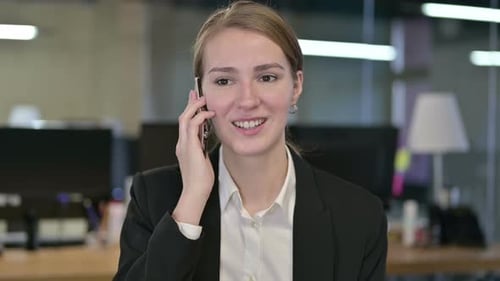 Businesswoman Talking on Cellphone in Modern Office