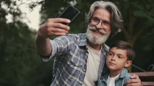 Stylish Grandfather and Grandson Taking a Selfie in a Park