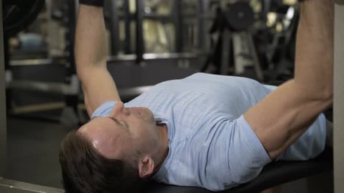 Close up image of man doing bench press at the gym.