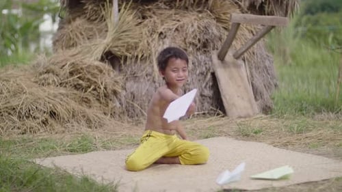 Young Boy Playing With Paper Airplane Outdoors