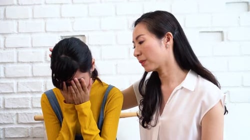 Asiatische Mutter tröstet weinende Tochter im elenden, gestressten, depressiven, traurigen Geisteszustand