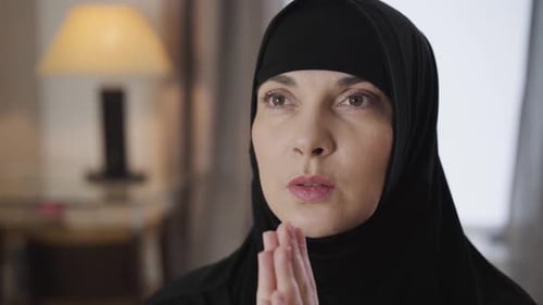 Nahaufnahme des Gesichts einer jungen schönen muslimischen Frau, die sich an den Händen hält und betet. Lady in Schwarz